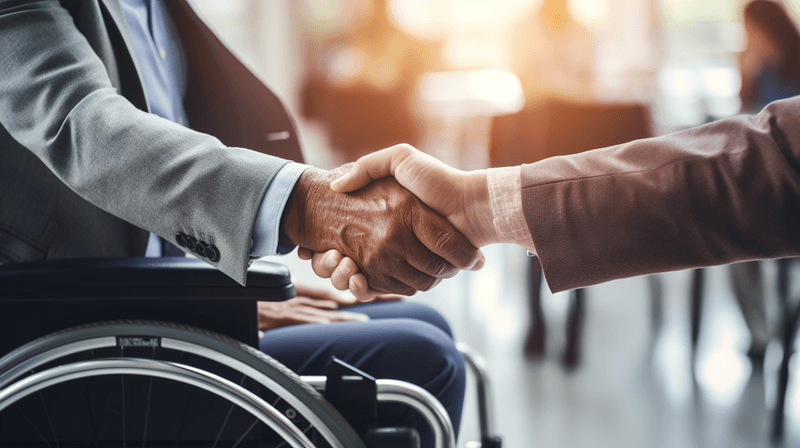 A man in a wheelchair shaking hands with another person.