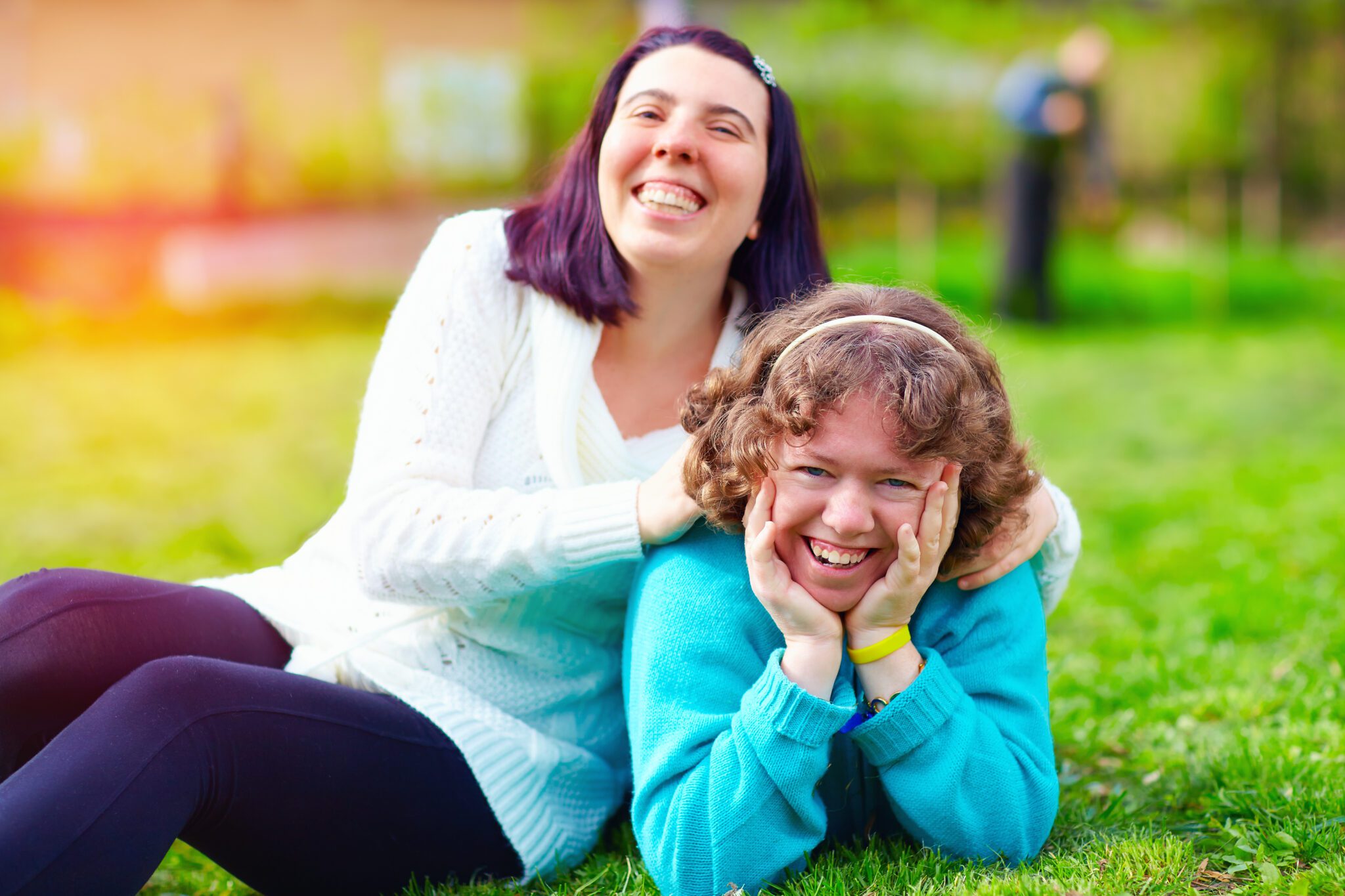 Two women are laying on the grass smiling.