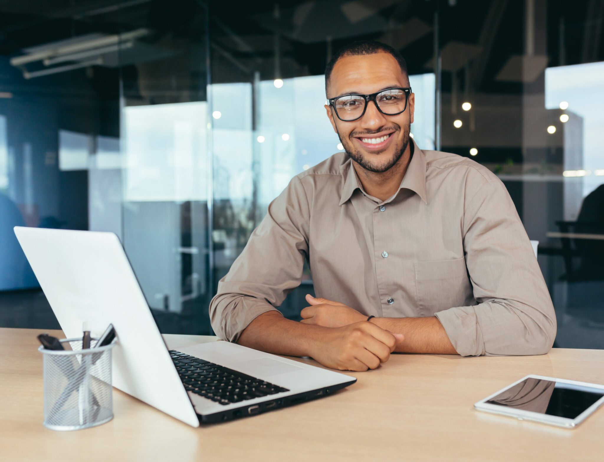 A man sitting at a table with two laptops.