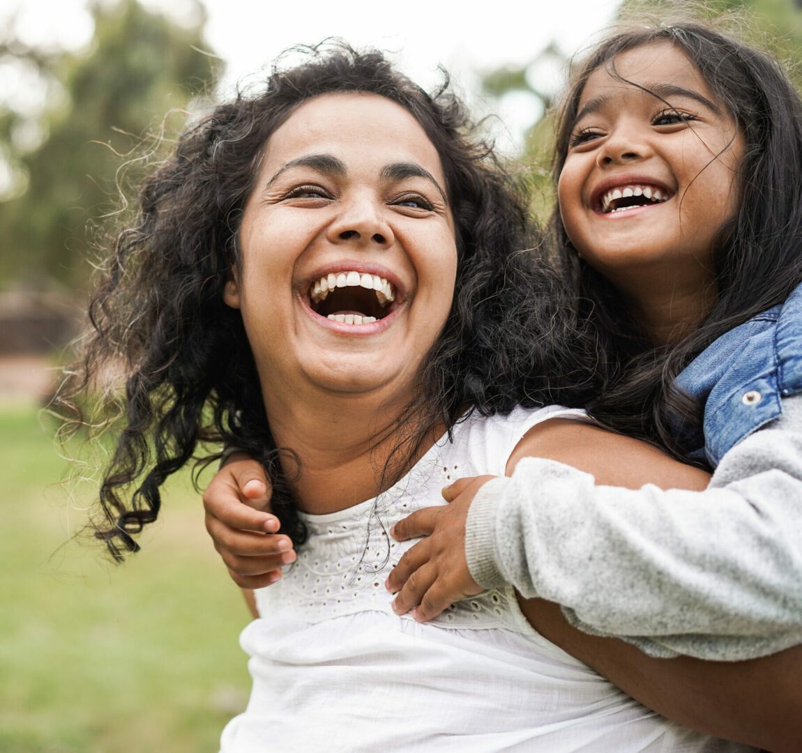 A woman and child are laughing together outside.