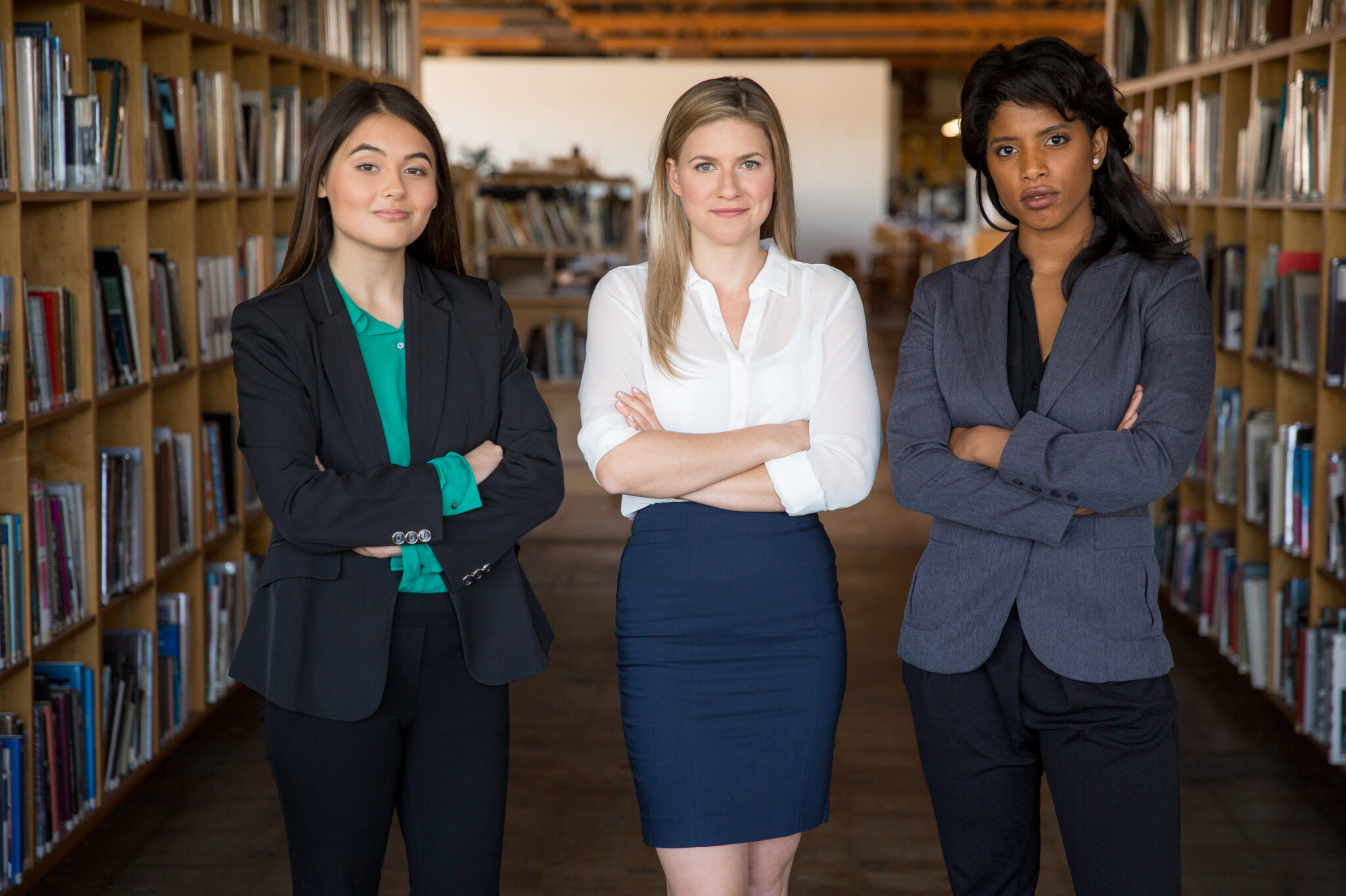 Three women standing in a room with their arms crossed.