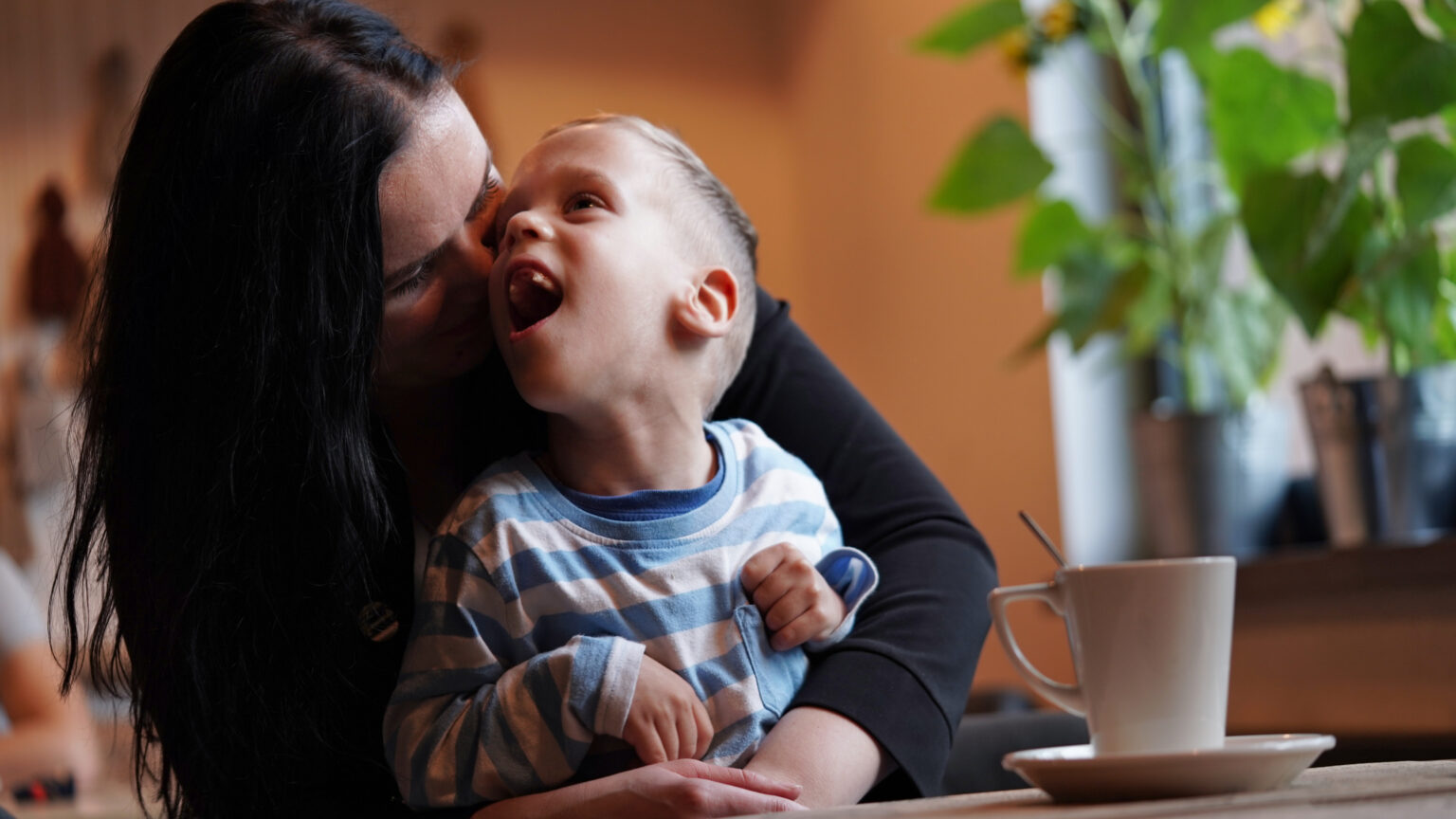 A woman kissing a child on the cheek.