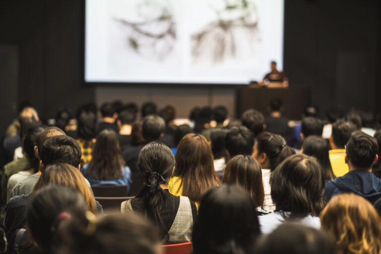 A group of people sitting in front of a projector screen.