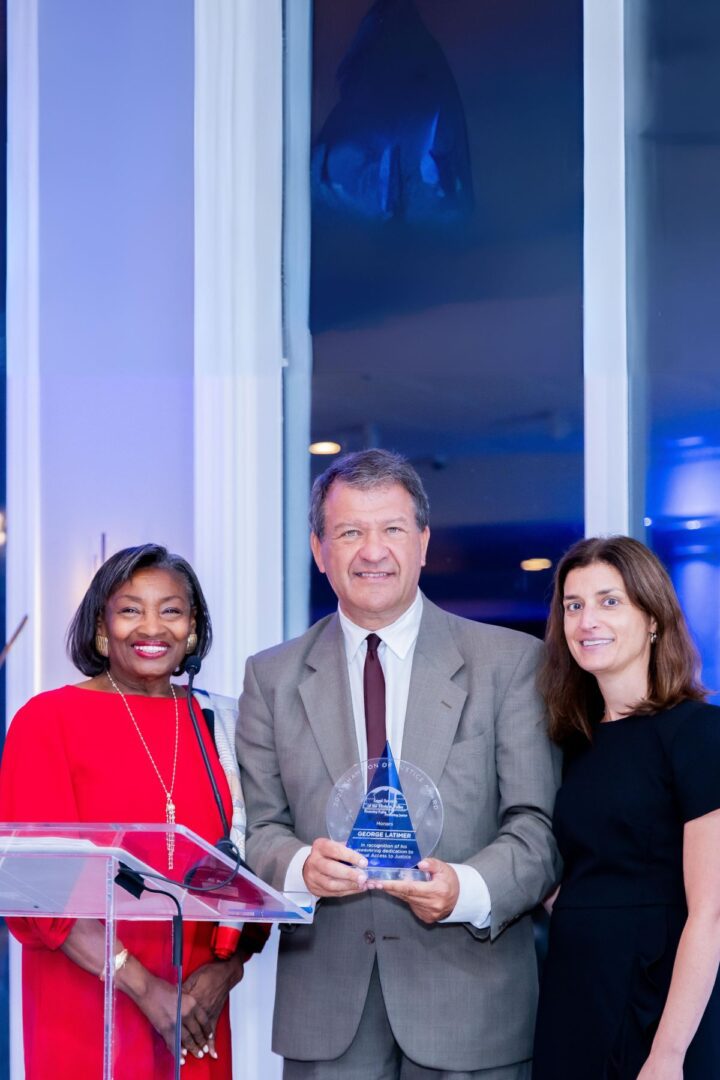 Three people standing in front of a podium holding an award.