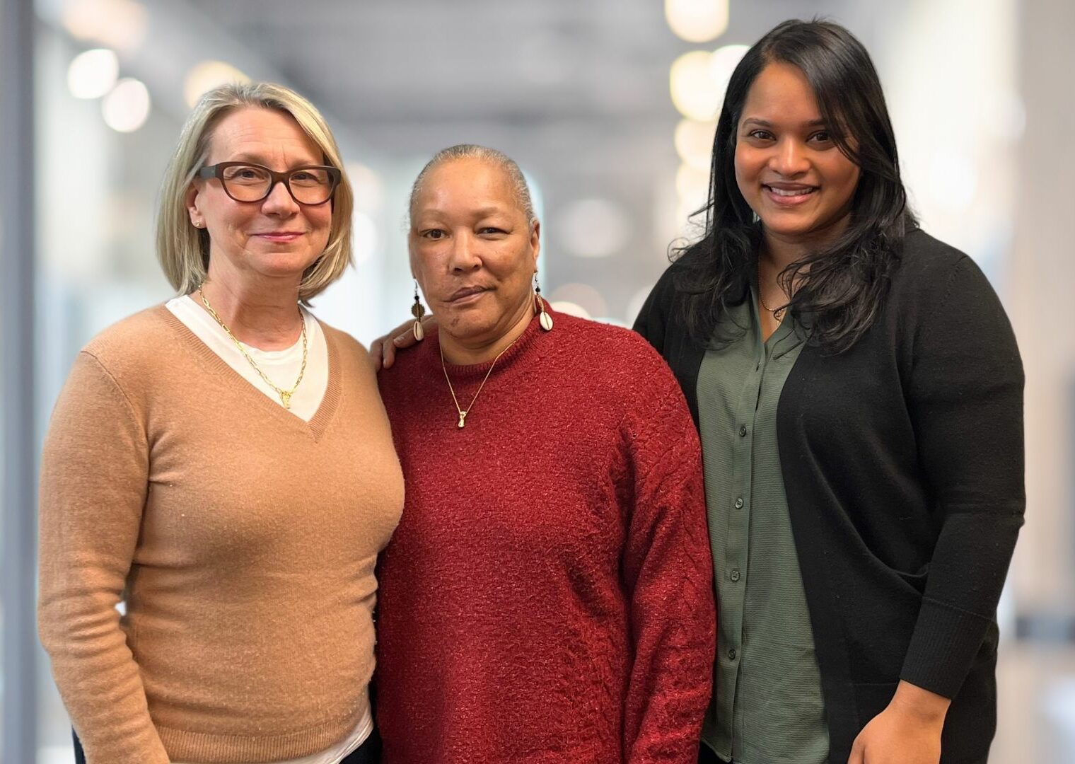 Three women standing next to each other in a room.