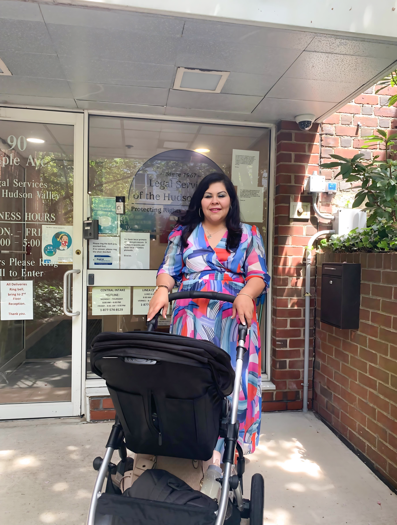 A woman pushing a stroller in front of a building.